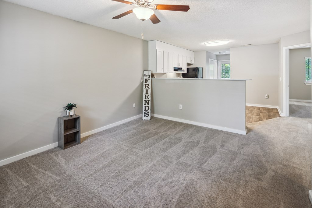 an empty living room and kitchen with a ceiling fan