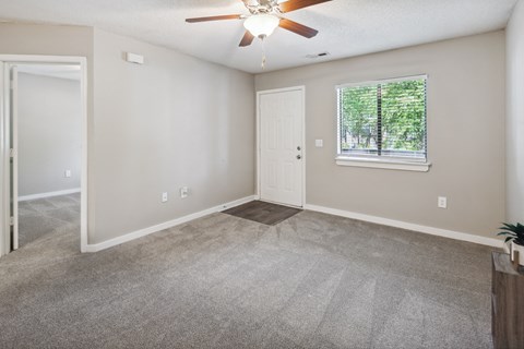 an empty living room with a ceiling fan and a window