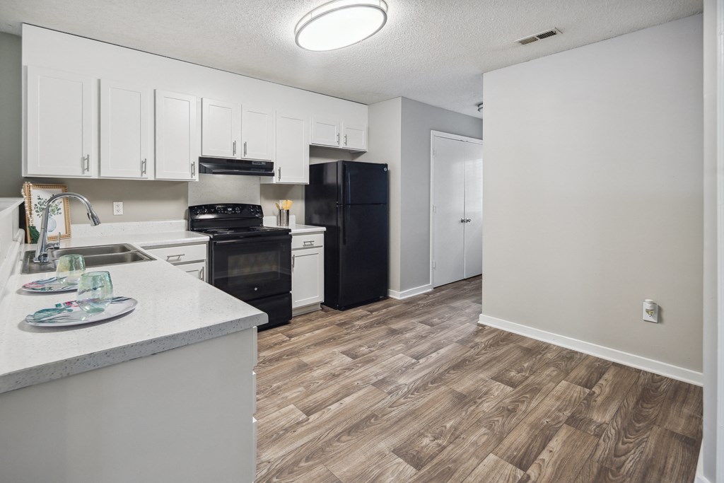an empty kitchen with white cabinets and black appliances