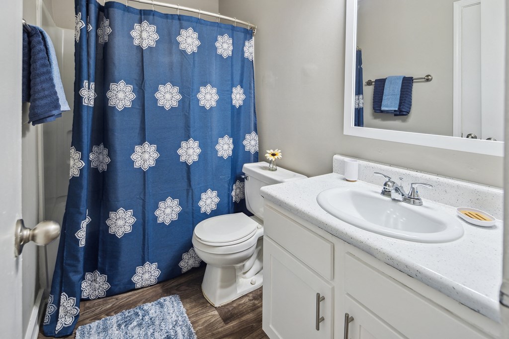 an updated bathroom with a blue shower curtain and a white sink and toilet
