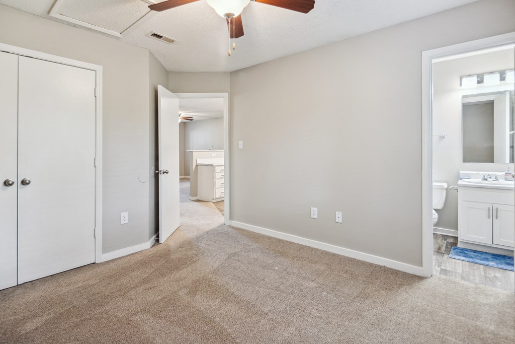 an empty living room with a ceiling fan and a bathroom