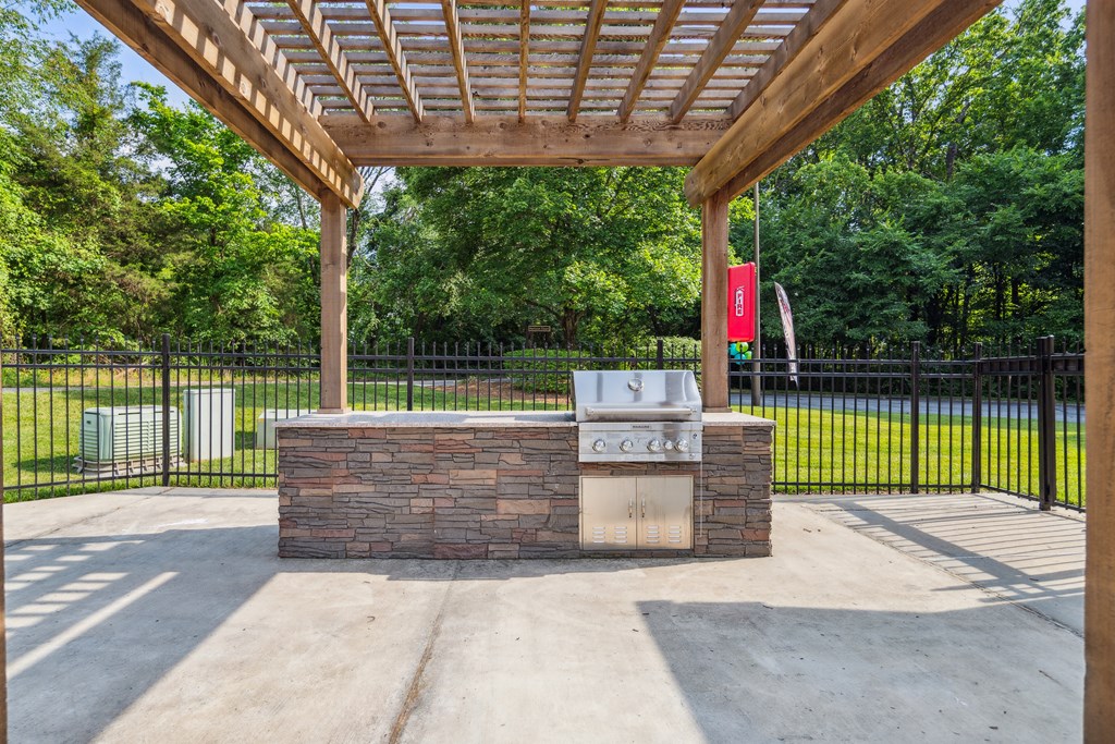 a covered pavilion with a barbecue grill in a park