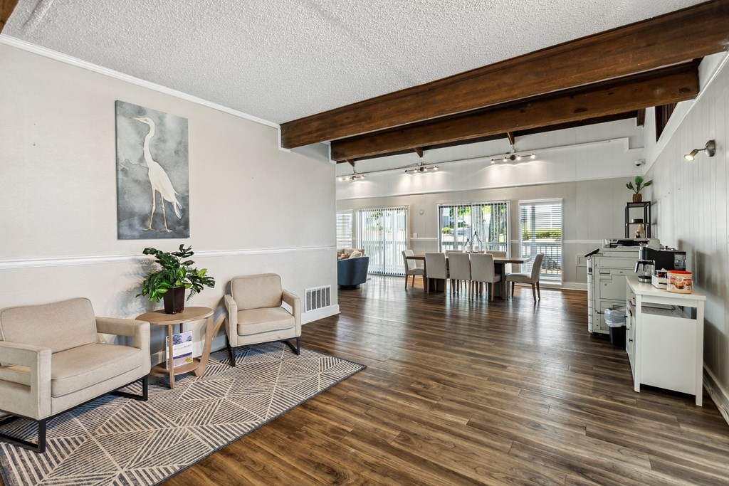 the living room and dining area of a home with a wood floor and white walls