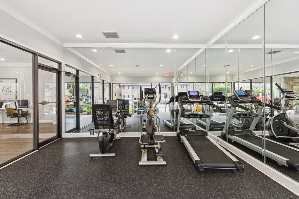 a gym with cardio equipment and glass walls