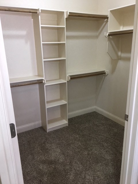 a walk in closet with shelves and empty shelves