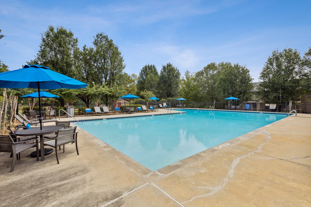 our resort style swimming pool is surrounded by patio furniture and umbrellas