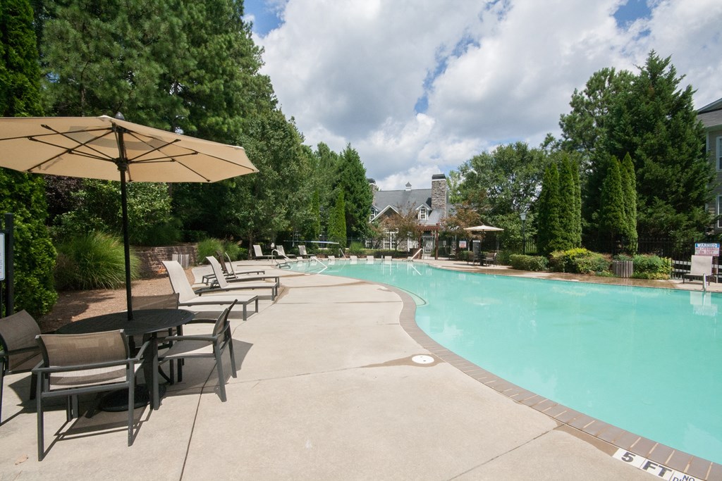 a swimming pool with chairs and umbrellas and trees