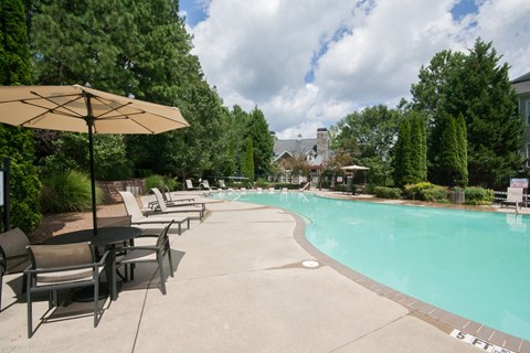 A pool surrounded by trees and chairs.