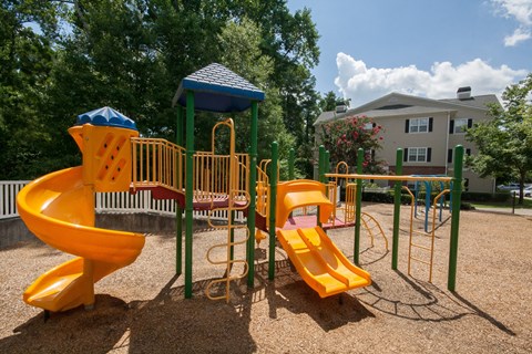 A playground with a yellow slide and a blue roofed structure.