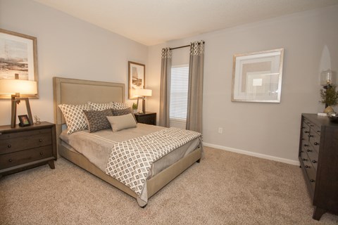 A bedroom with a bed, dresser, and nightstand.