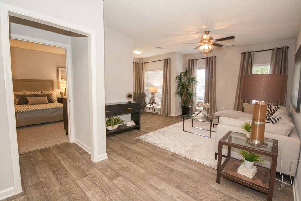 A living room with a brown rug and a glass coffee table.