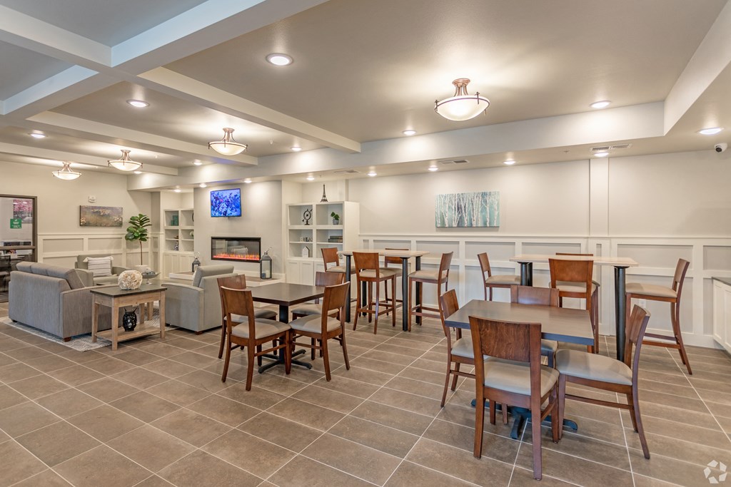 a community room with tables and chairs and a fireplace