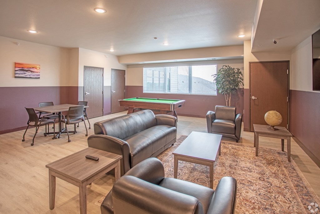 a community room with couches tables and chairs and a pool table
