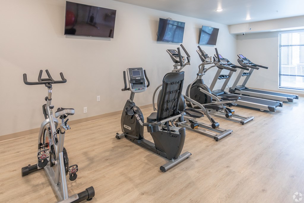 a row of exercise bikes in a gym with a tv on the wall