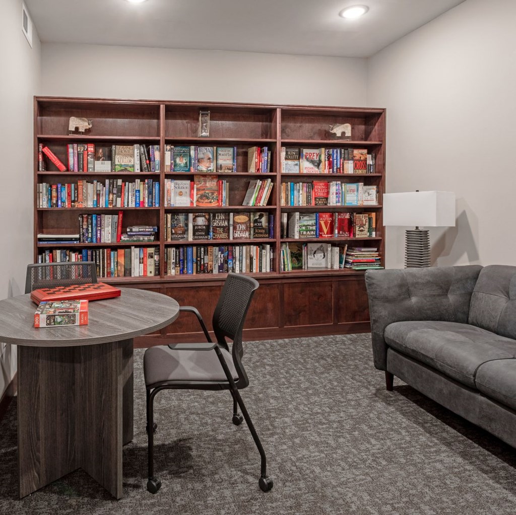 a library with a table and chairs and a bookshelf