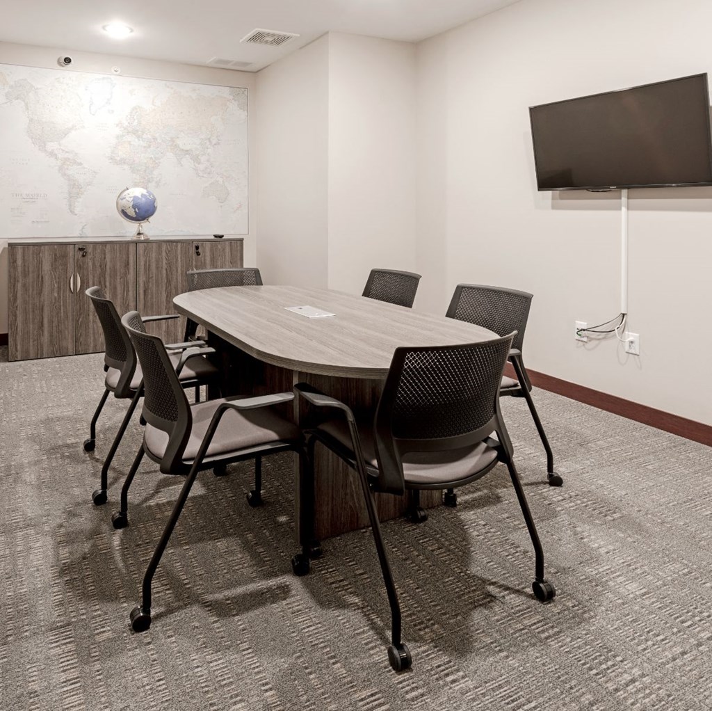a conference room with a table and chairs and a tv