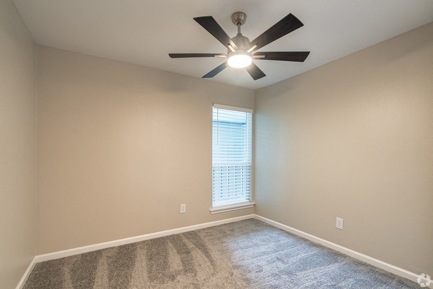 a bedroom with a ceiling fan and a window at The Wilshire, Lake Charles, Louisiana