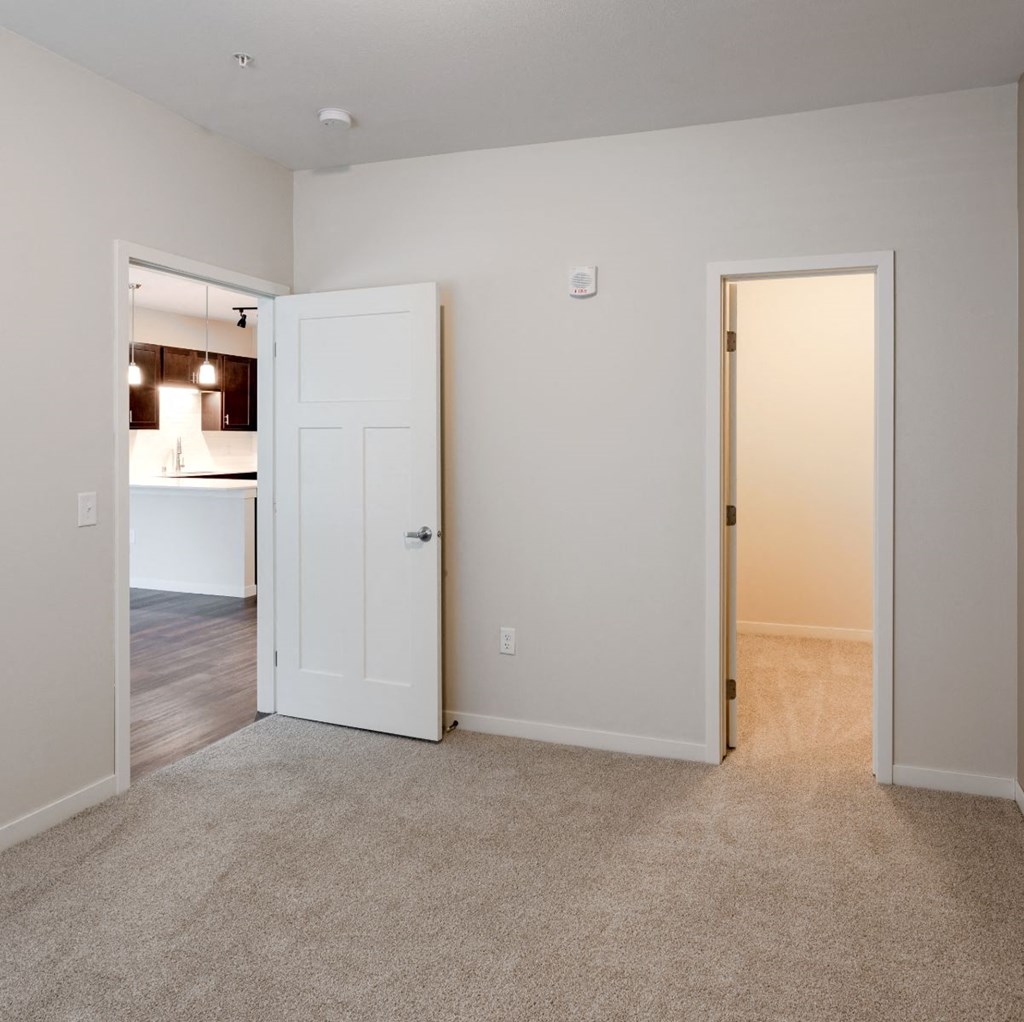 an empty living room with an open door to a kitchen