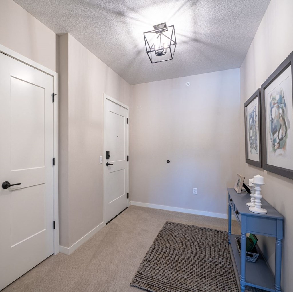 a hallway with a blue table and a door to a room with white walls