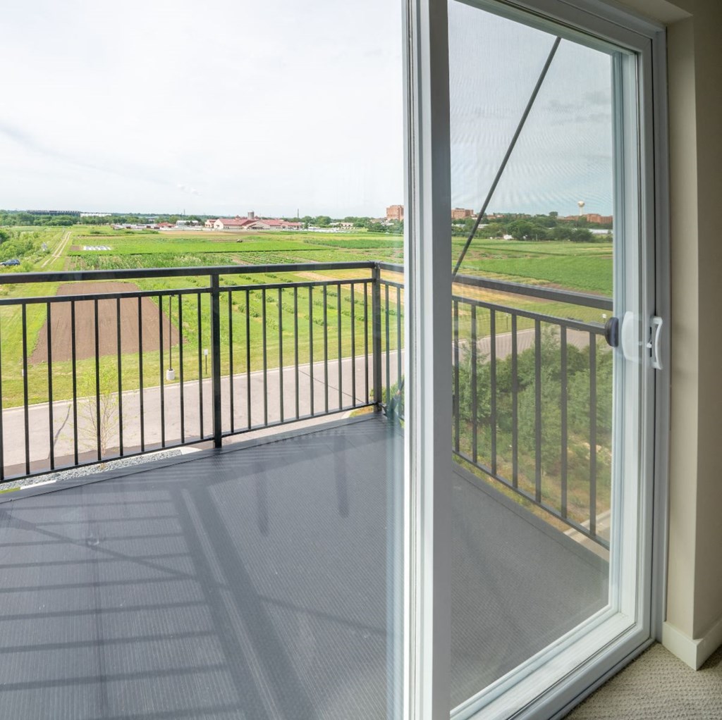 a balcony with a glass door and a view of a field