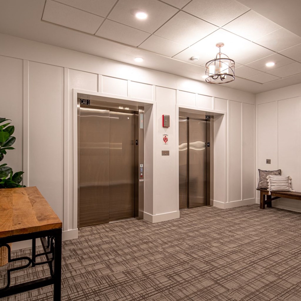 a lobby with two elevators and a table and a chair