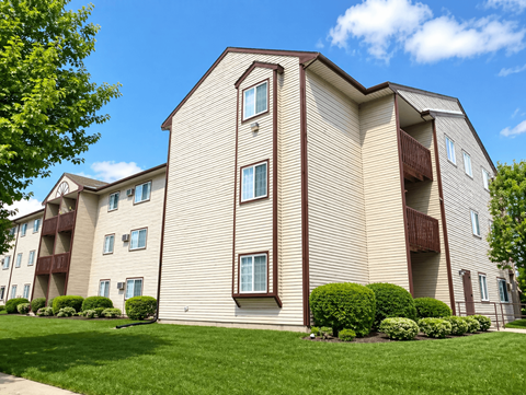 A large apartment building with a green lawn in front.