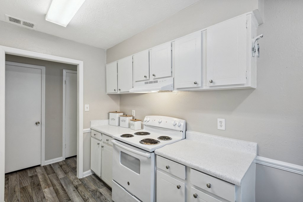 a white kitchen with white cabinets and a white stove top oven