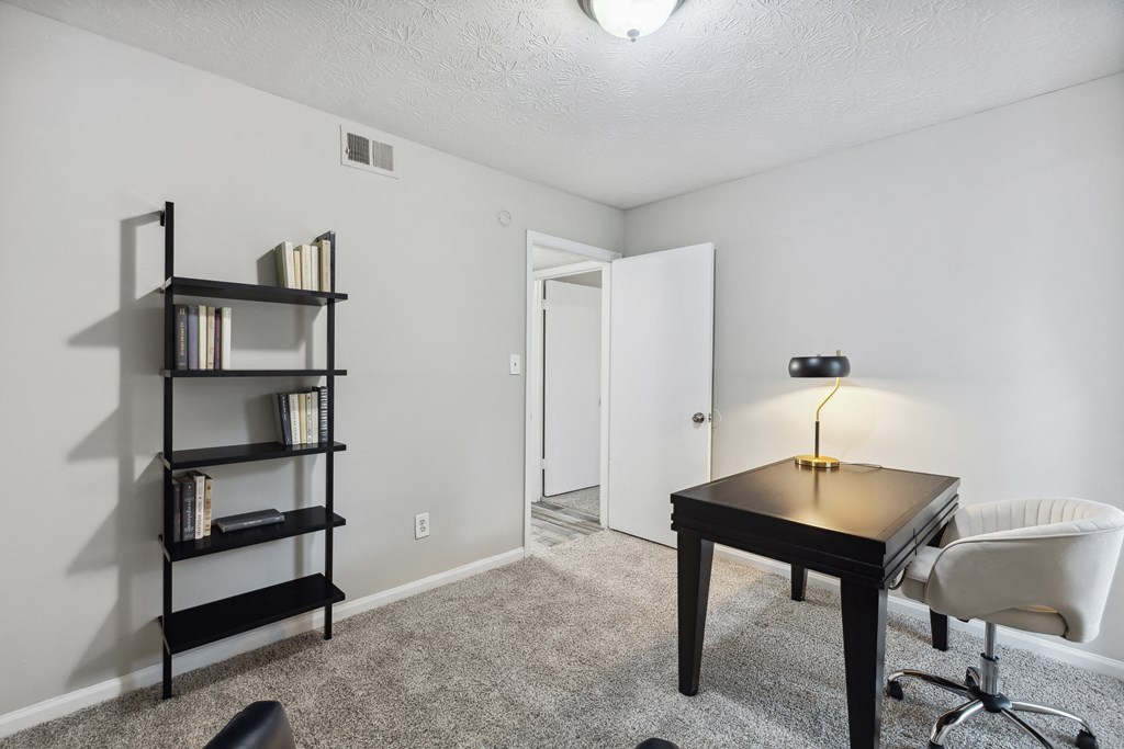 an empty room with a desk and a chair and a book shelf