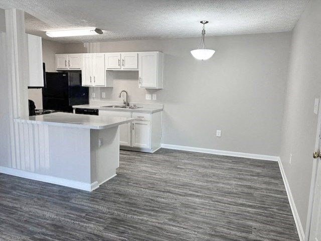 A kitchen with a black fridge and white cabinets.