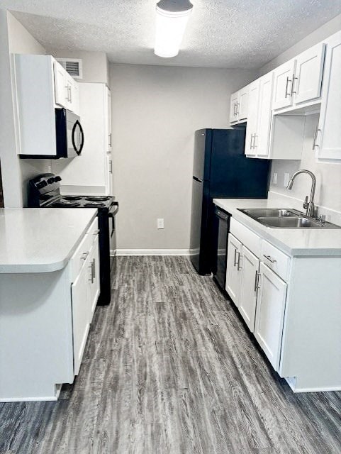 A kitchen with white cabinets and a black refrigerator.