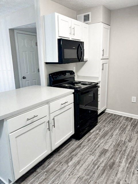 A black microwave is on top of a black stove.