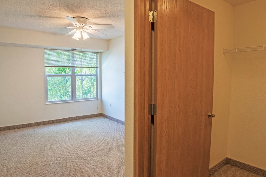 an empty bedroom with a closet and a window