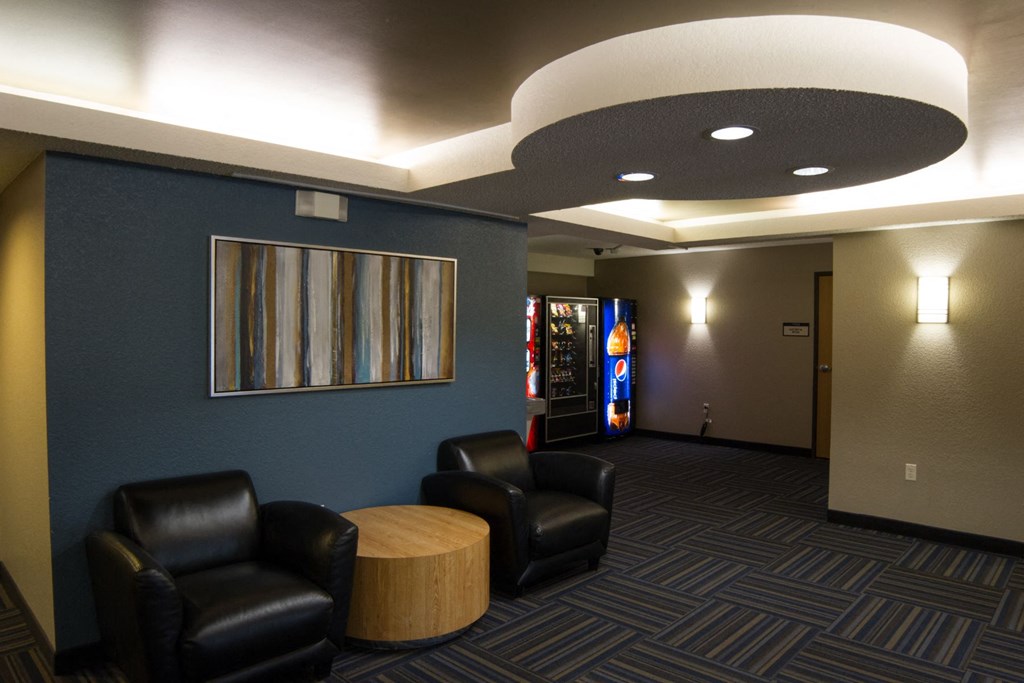 a lobby with black leather chairs and a blue wall and a vending machine