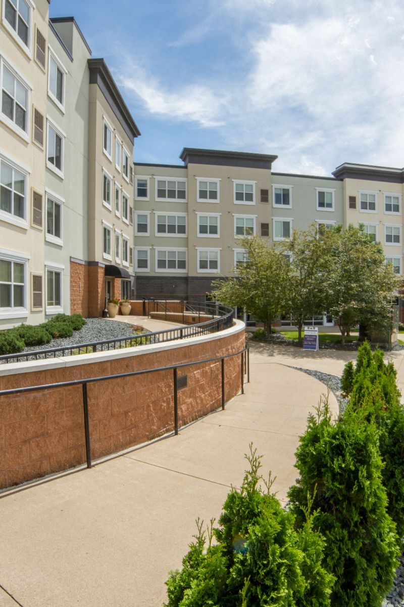 a walkway in front of an apartment building with a courtyard