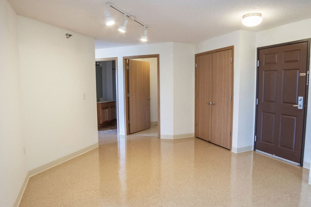 an empty living room with a hallway and two doors