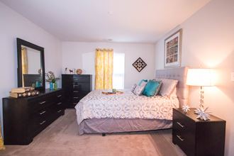 a bedroom with a large bed and dresser and a window