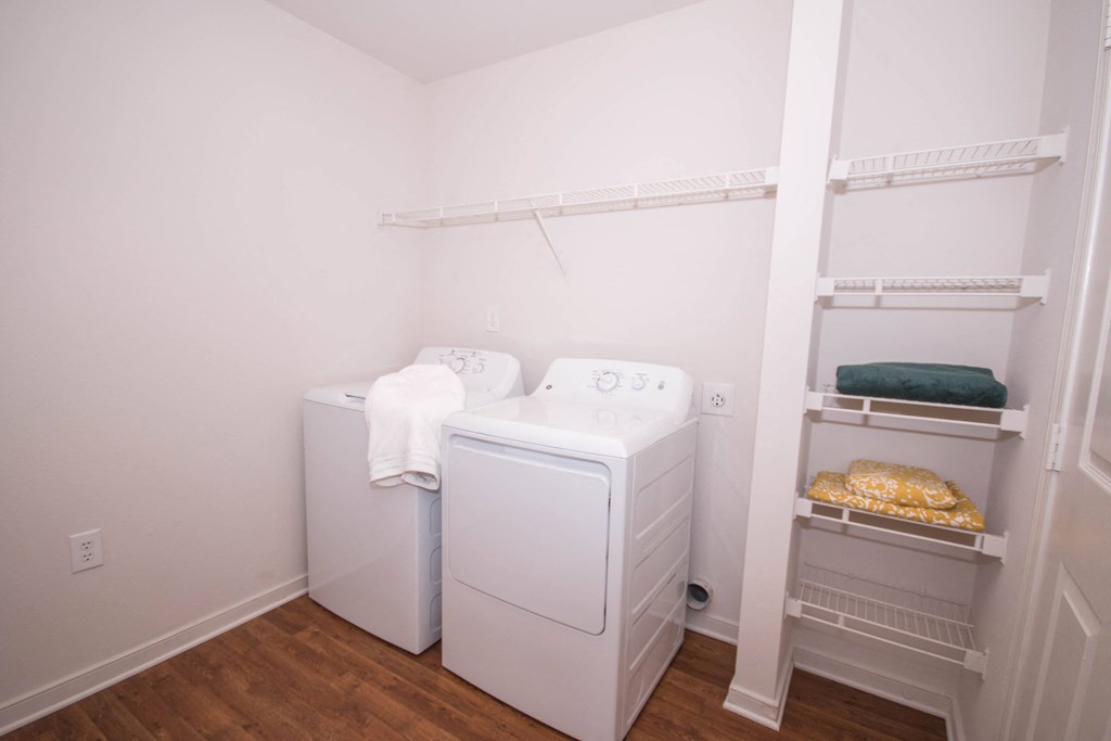a room with a washer and dryer in it and a closet with shelves