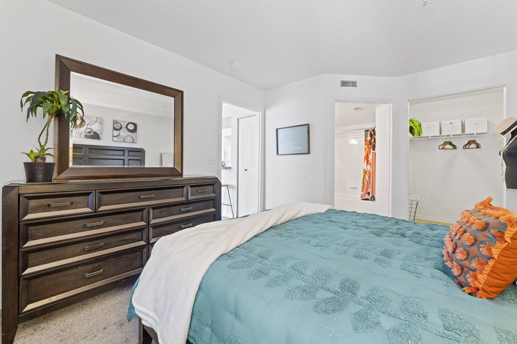 a bedroom with a bed and a dresser and a mirror