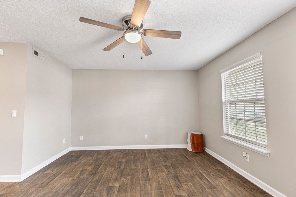 an empty living room with a ceiling fan and a window