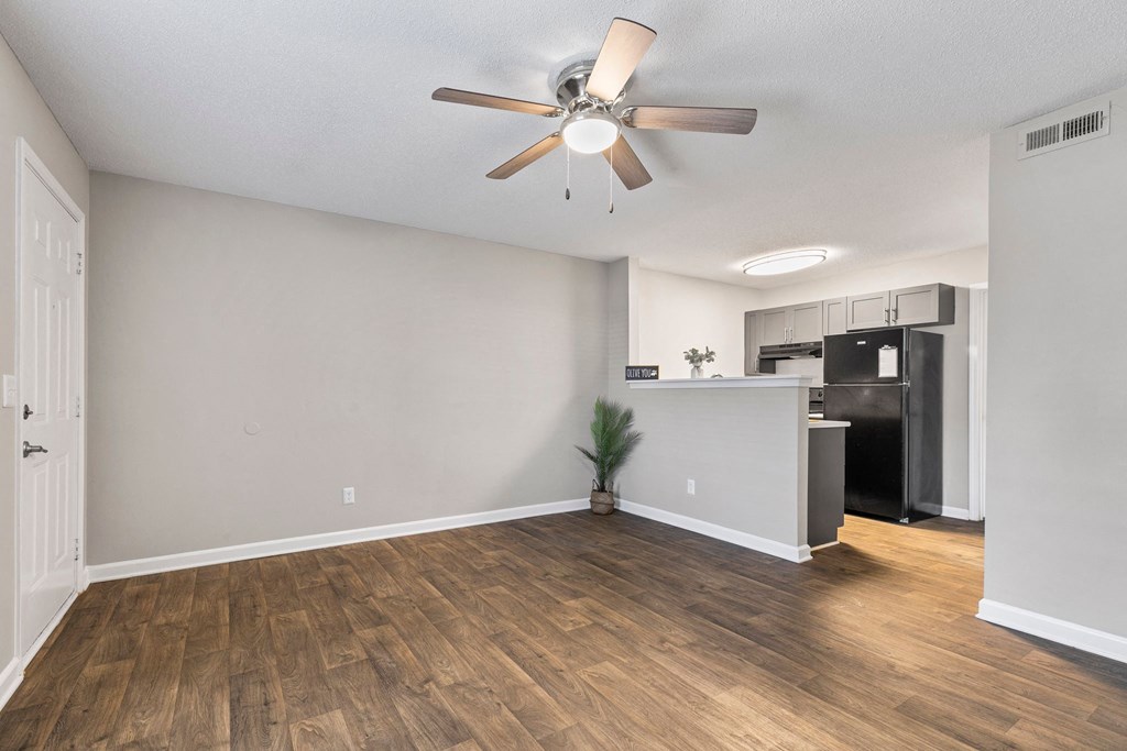 A room with a ceiling fan and wooden flooring.