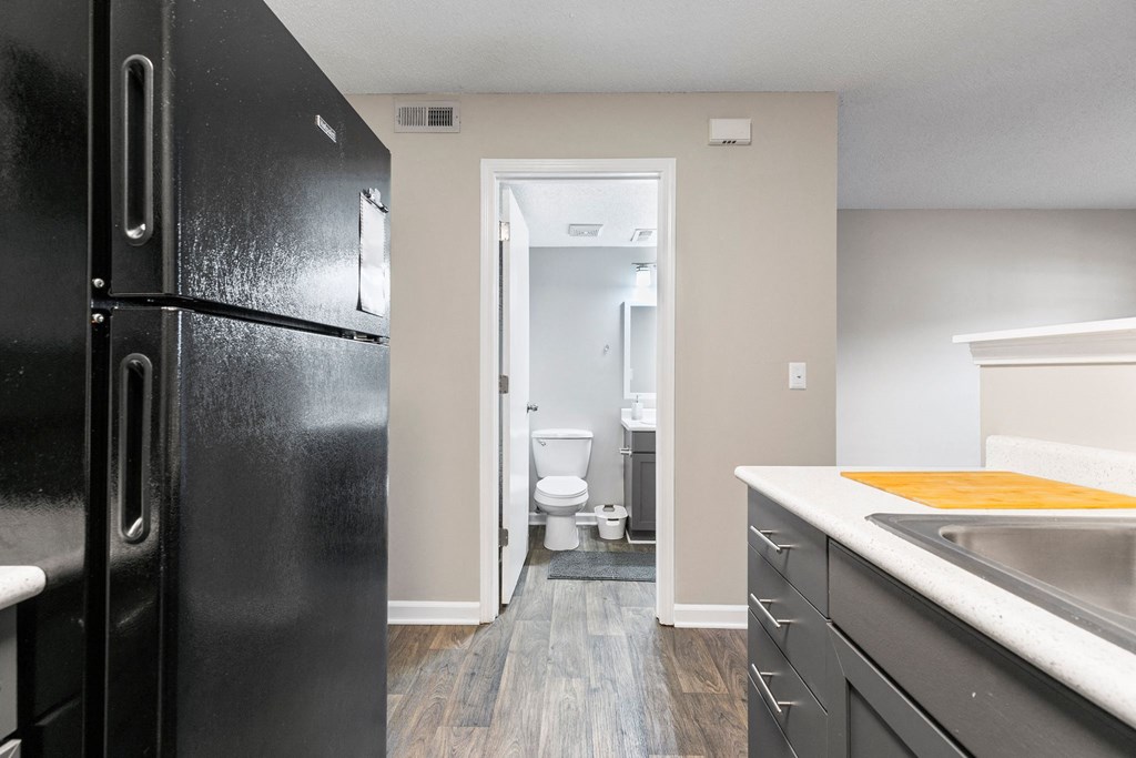 a kitchen with black appliances and a black refrigerator and a bathroom with a toilet