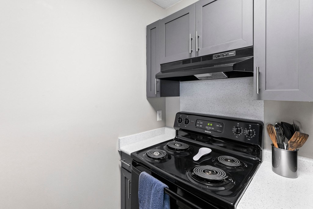 a kitchen with a stove and a microwave and white cabinets