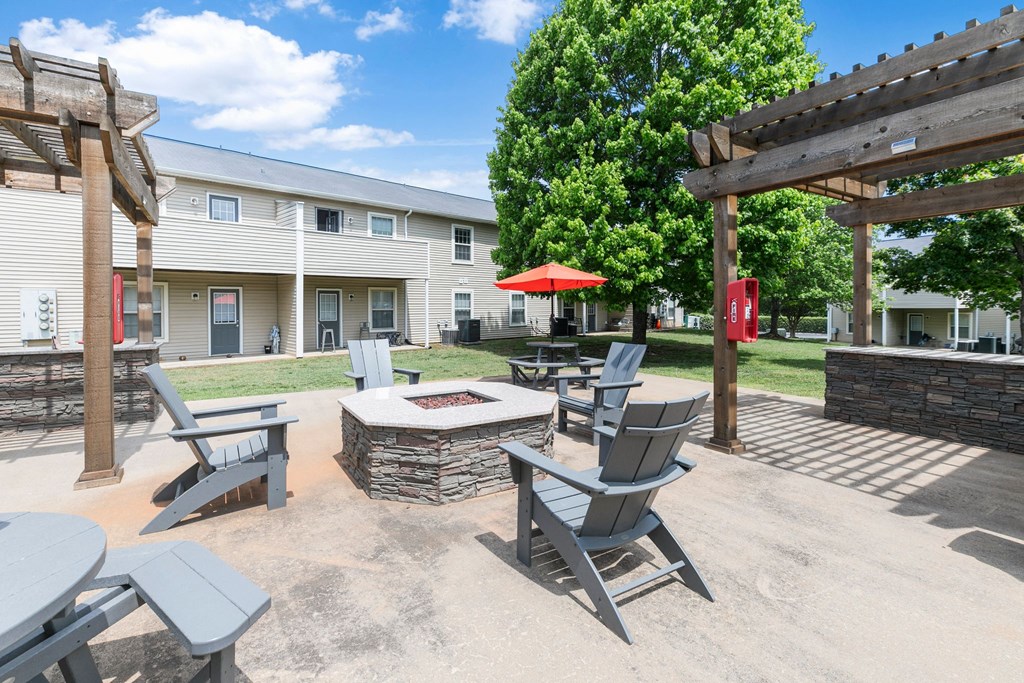 A patio with chairs and a fire pit in front of a building.