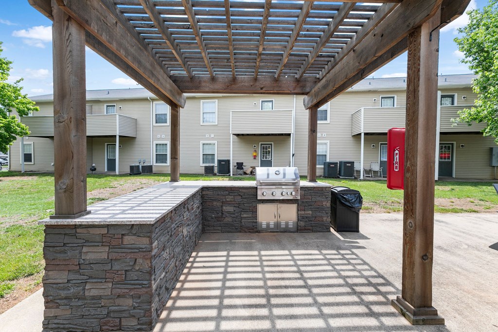 a covered patio with a grill in front of an apartment building