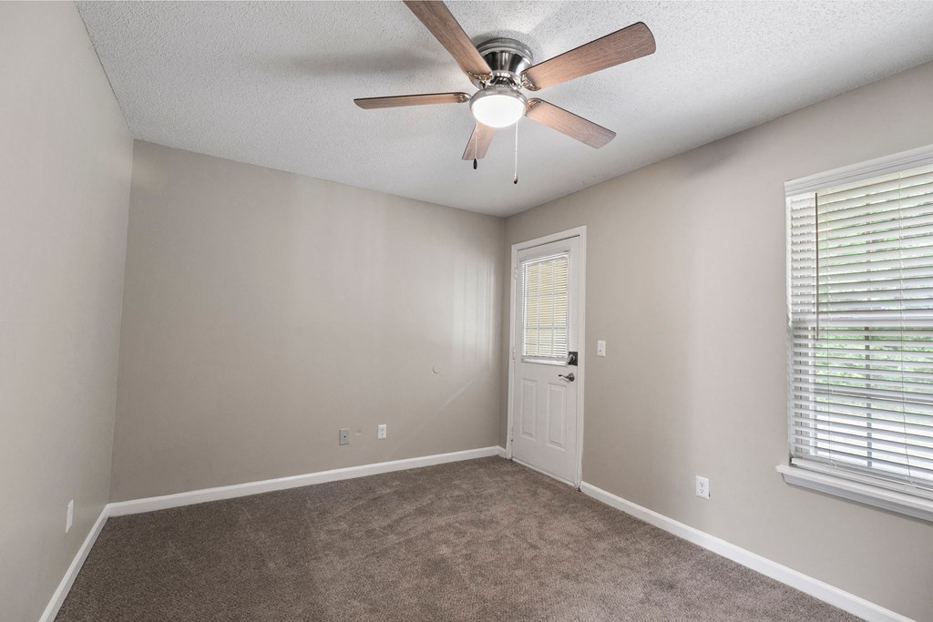 A room with a ceiling fan and a door.