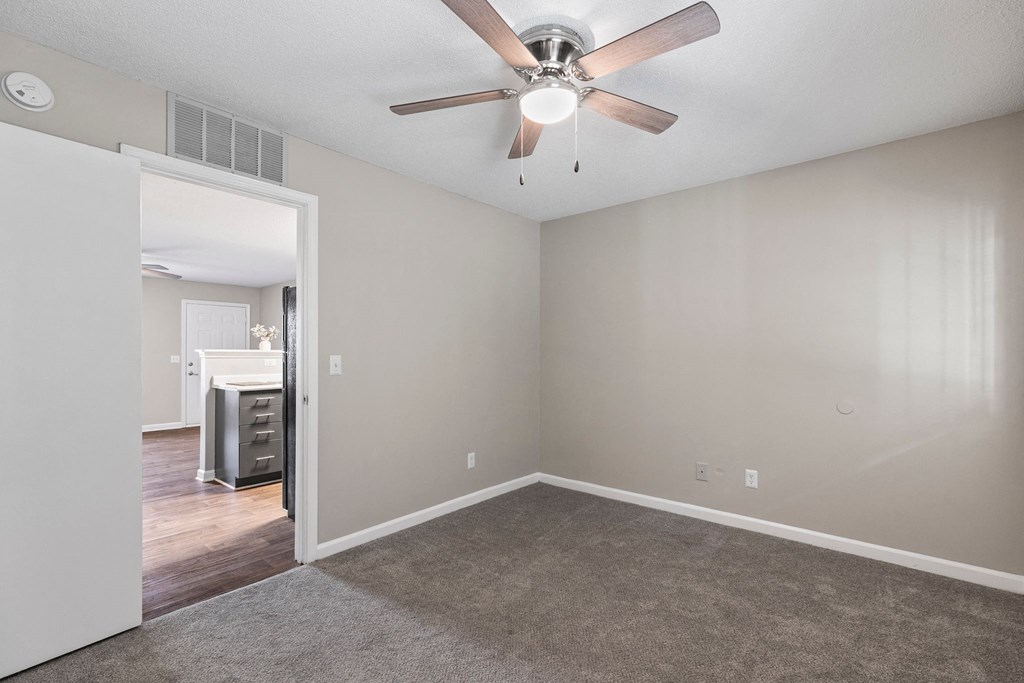 an empty living room with a ceiling fan