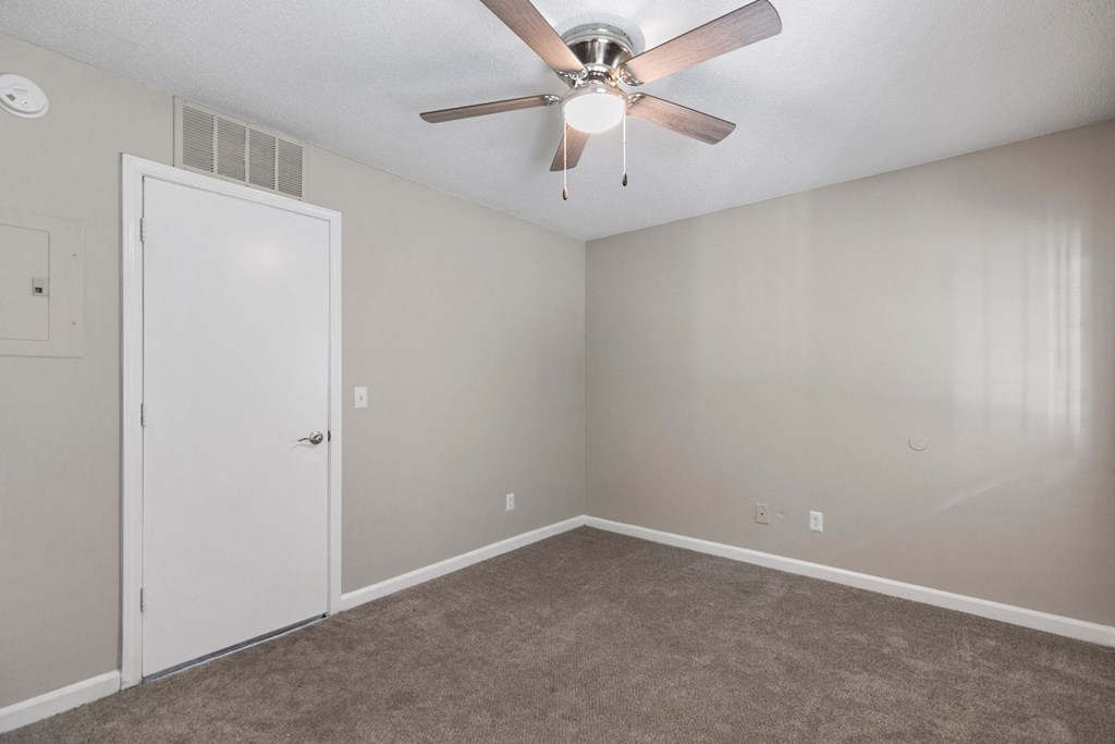 A room with a ceiling fan and carpeted floor.