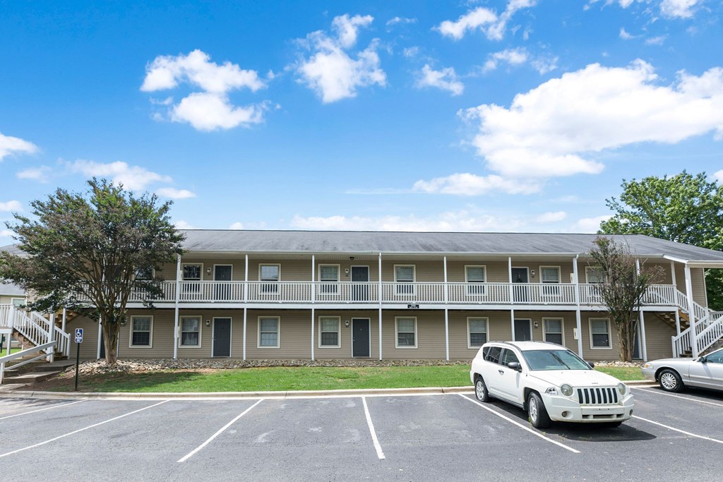 A white car is parked in a parking lot in front of a building.