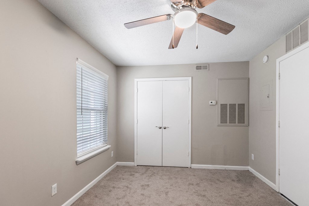 an empty bedroom with a ceiling fan and a closet