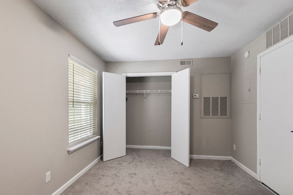 an empty bedroom with a ceiling fan and a closet